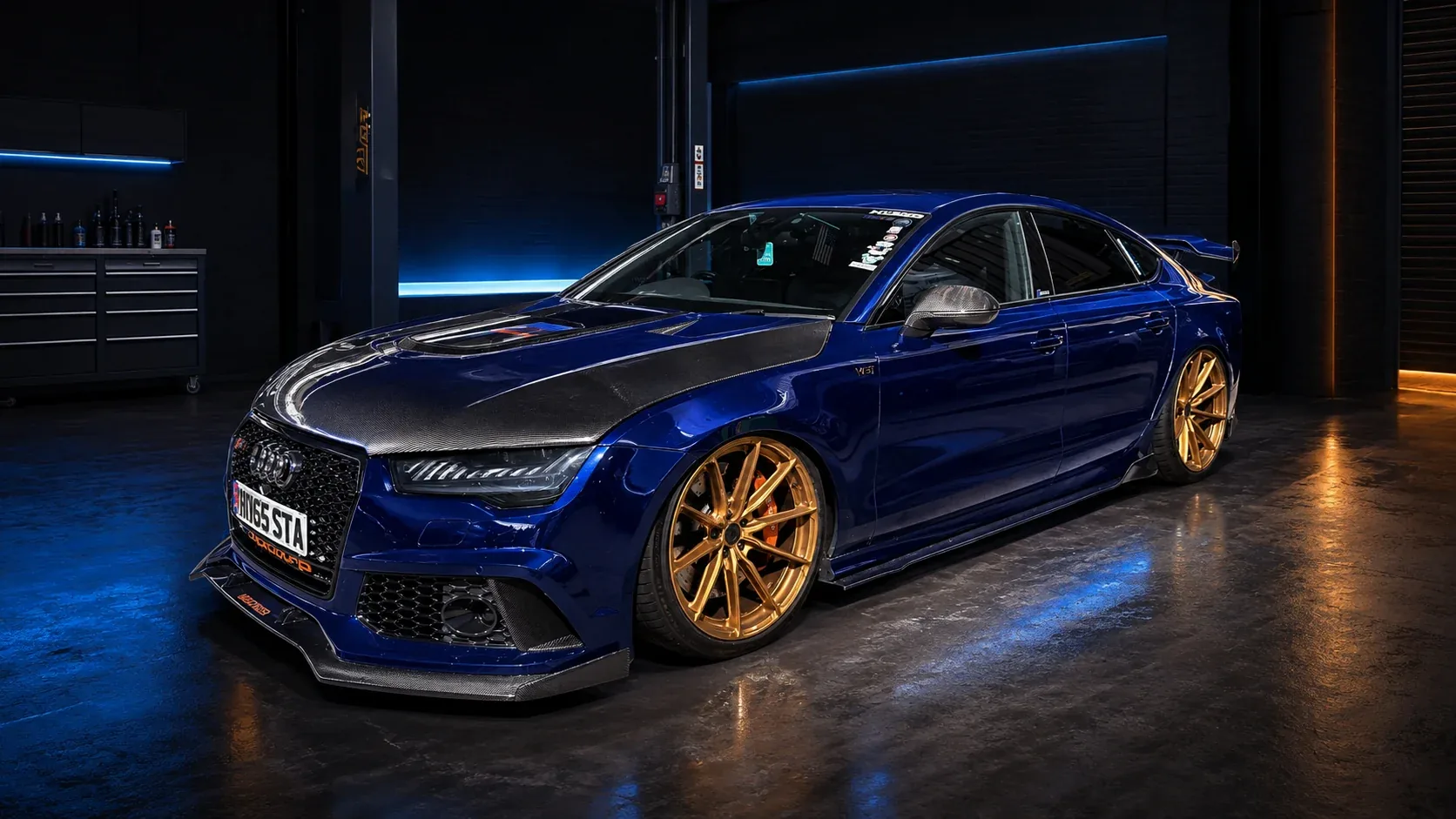 Cinematic front three-quarter view of the current blue Torque Monsta Audi S7 with bronze wheels and its carbon split rear wing visible